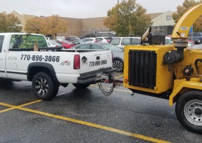 A tow truck is towing a large yellow tractor.